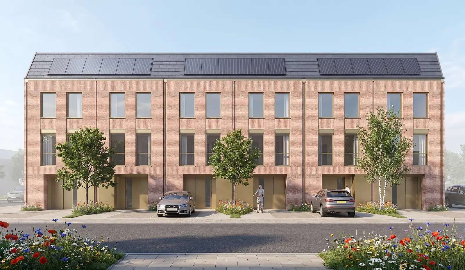Proposed townhouses seen from the front, showing the pitched roofs with solar panels, dedicated parking and wildflower planting